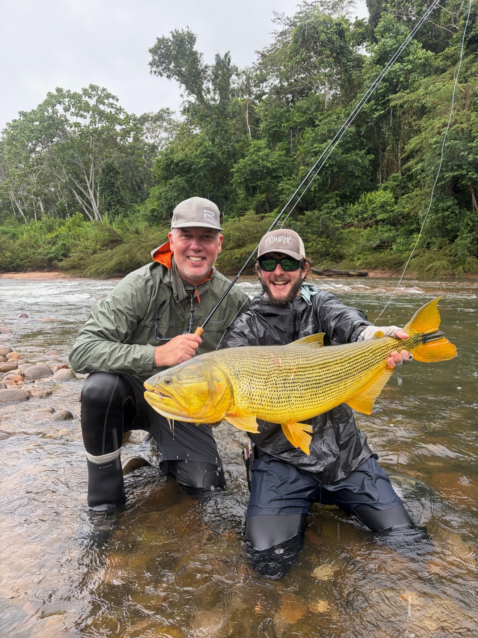 Two anglers with a dorado in their rain gear